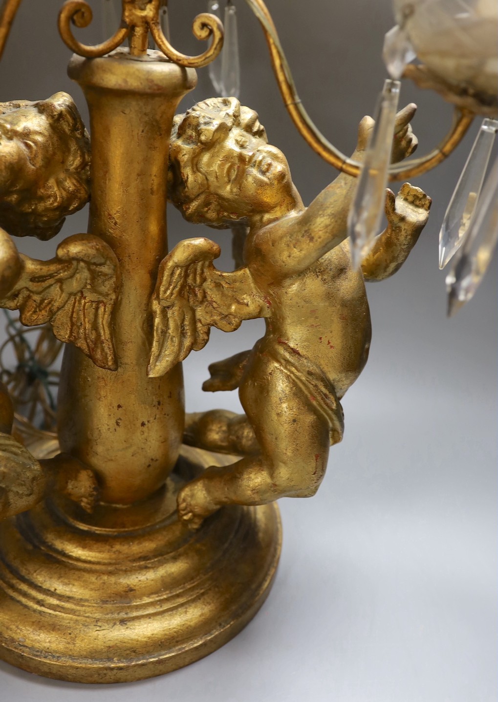 An Italian three branch gilt cherubs decorative lamp with cut glass lustre drops - 64cm high